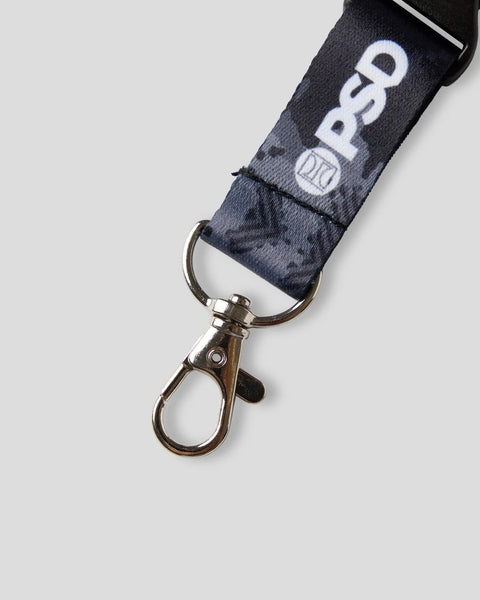 Digital camouflage lanyard with white text and metal clip attachment.