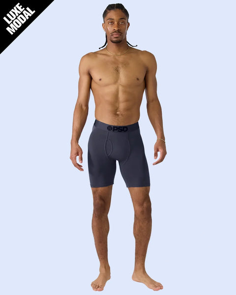 Man wearing dark navy modal boxer briefs with branded waistband against light blue background.