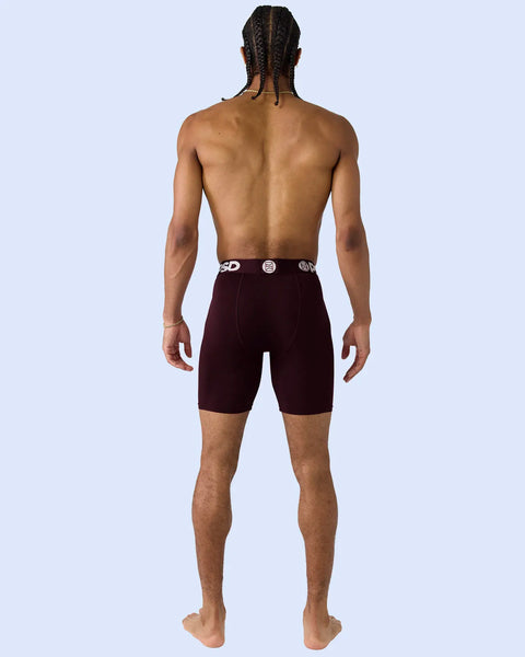 Man wearing burgundy modal shorts with branded waistband, back view.