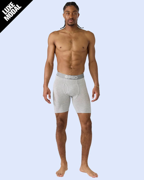 Man wearing heather gray modal shorts with PSD waistband, standing against light blue background.
