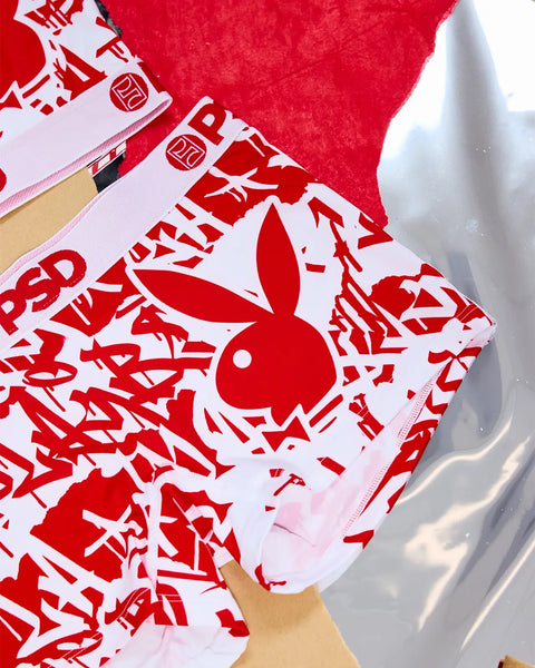 Red and white Playboy tags with bunny logo and text print on fabric.