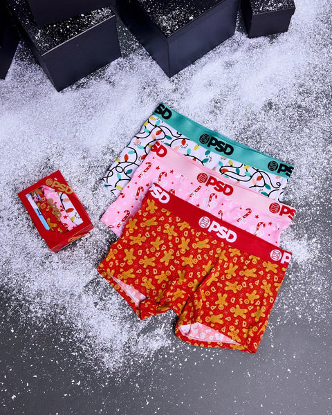 Three modal underwear briefs in red, pink, and turquoise with festive patterns including candy canes and gingerbread, display
