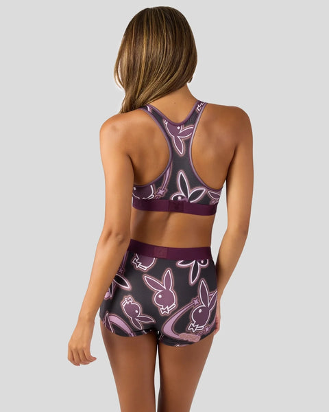Purple sports bra and shorts set with neon bunny logo pattern on dark background.