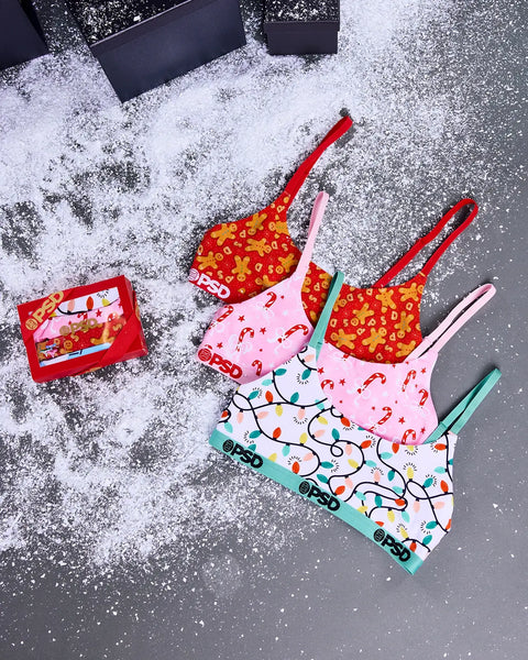 Three modal bralettes in red with gingerbread print, pink with candy cane print, and mint with colorful light garland print, 