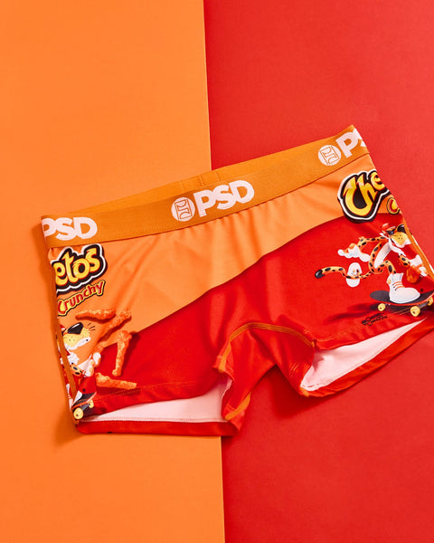 Red and orange Cheetos Crunchy branded underwear with elastic waistband on split orange and red background.