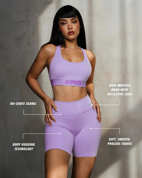 Lavender sports bra and shorts set with high-waisted band and reflective logo detail on model.
