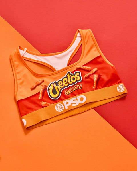 Orange and red sports bra with Cheetos Crunchy branding and crunchy snacks printed on front against divided orange and red ba