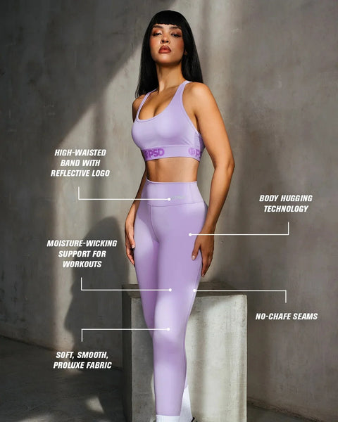 Woman wearing lavender sports bra and high-waisted leggings with reflective logo band.